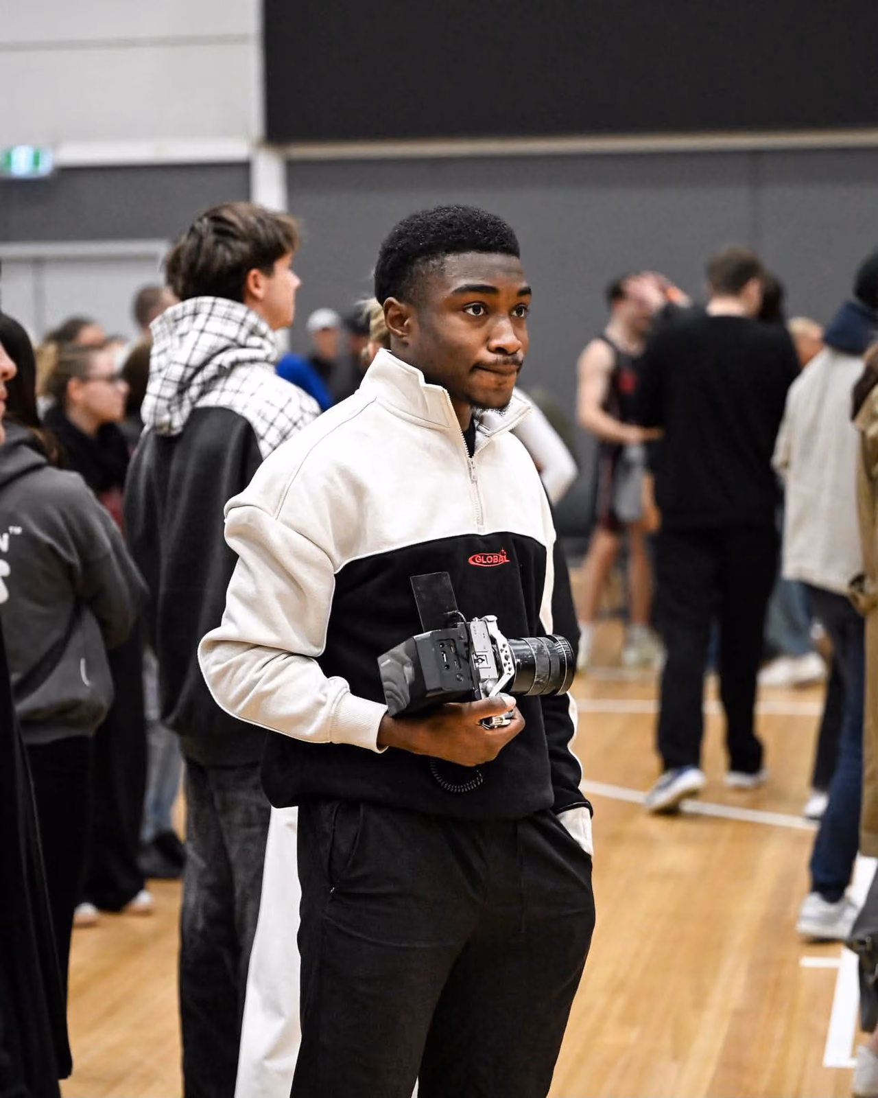 Olu filming from the sideline during a basketball game