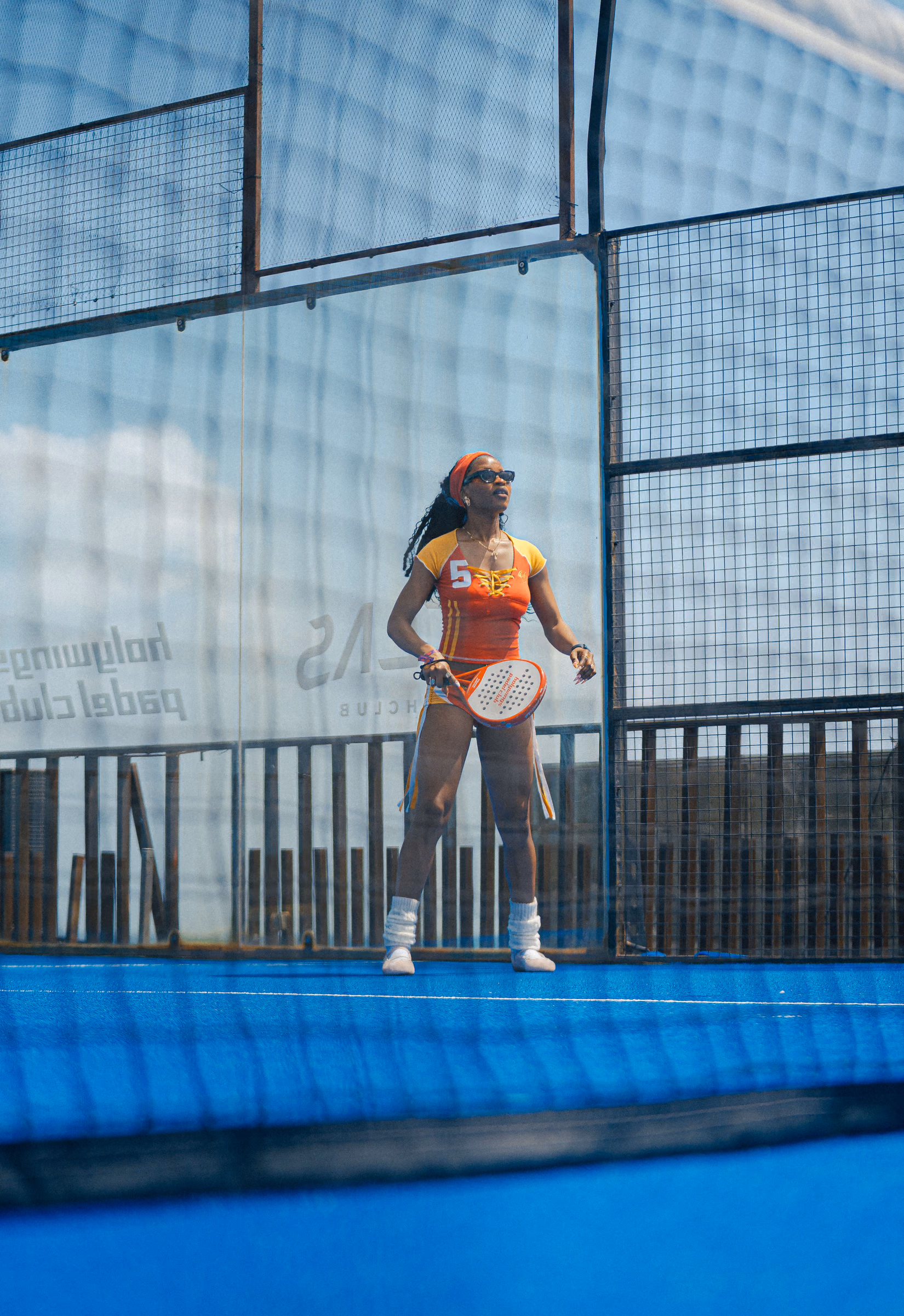 Padel player waiting with her racket on a blue outdoor court