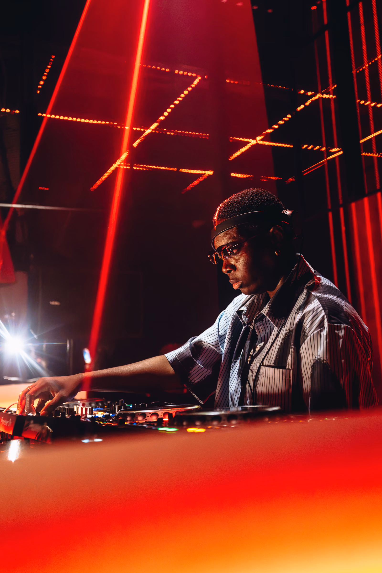 DJ mixing beneath vivid red stage lights
