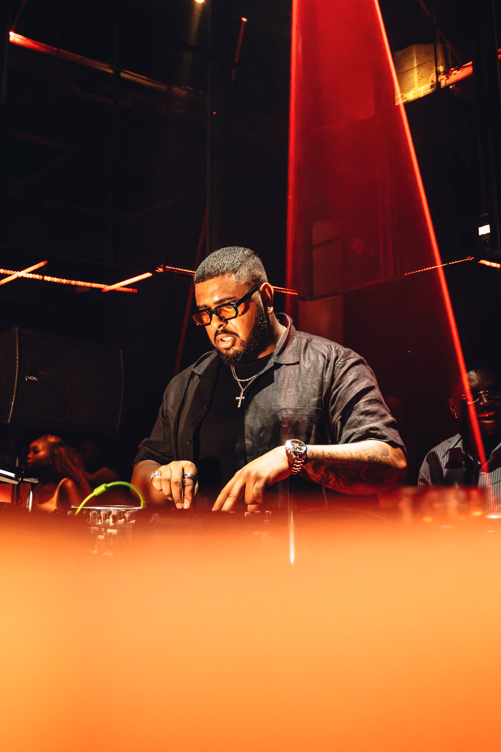 DJ performing beneath angular red stage lights