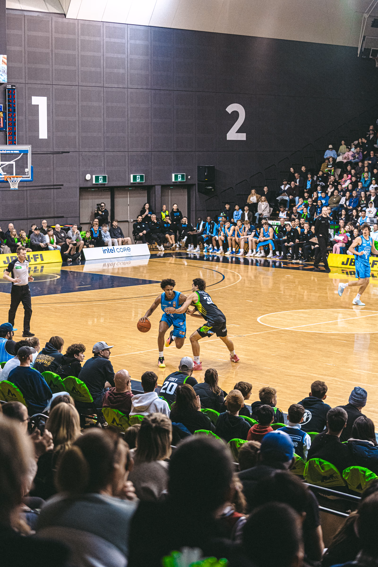 Two basketball players contesting possession during a packed game