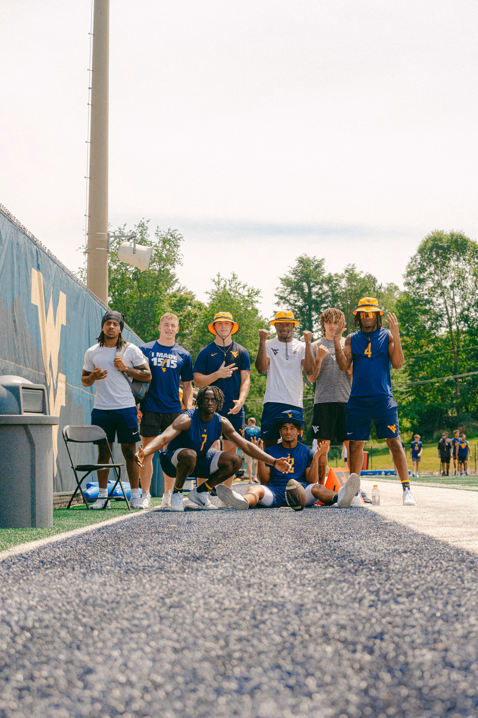 Group of football players posing together beside the field