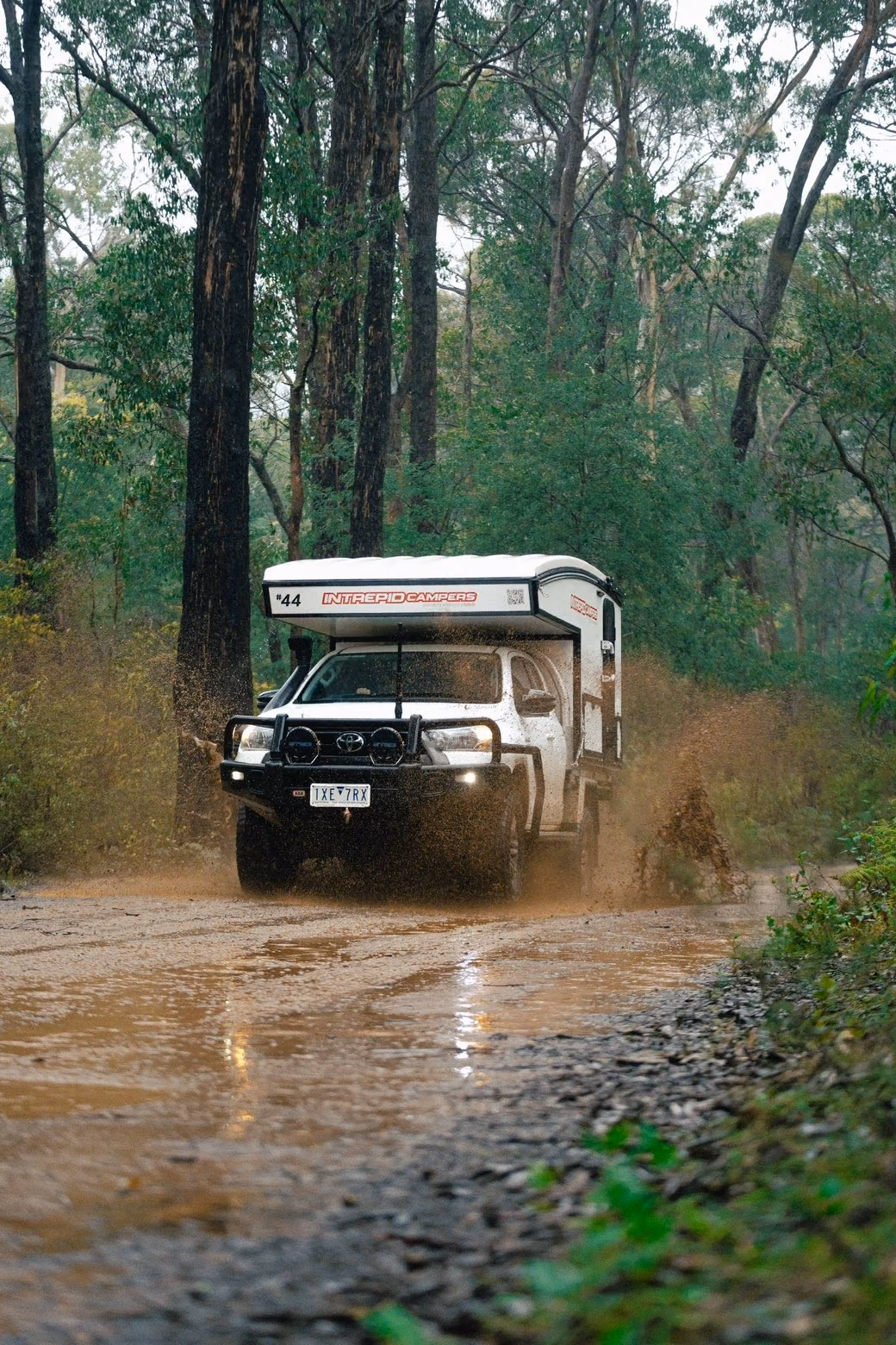Off-road vehicle driving through a muddy forest track